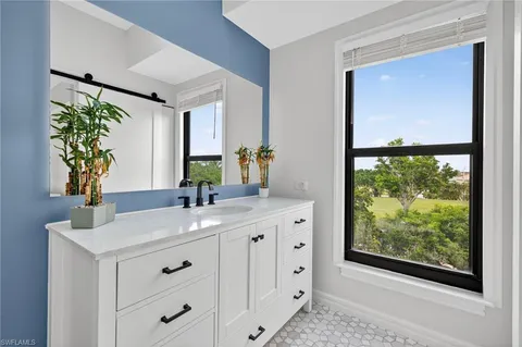a bathroom with a granite countertop sink mirror and window