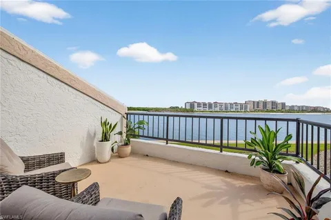 a balcony with potted plants and ocean view
