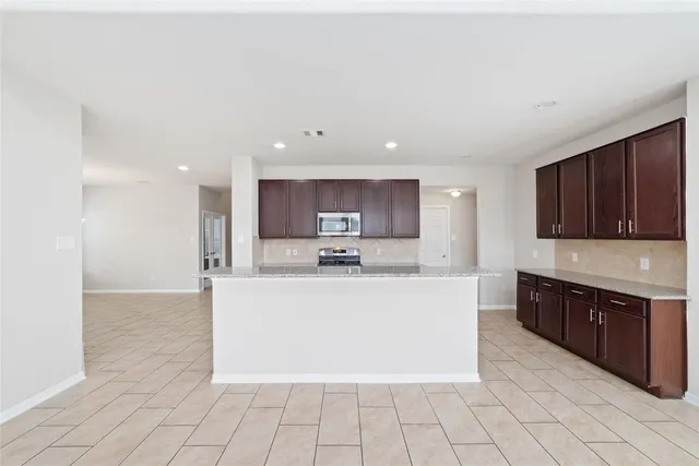 a large white kitchen with stainless steel appliances granite countertop a large counter top and a stove