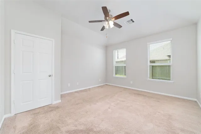 an empty room with windows and fan