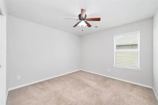 an empty room with a window and a ceiling fan