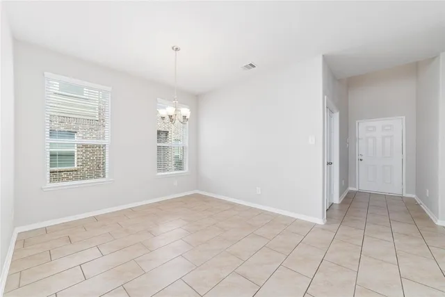 a view of an empty room with window and chandelier fan