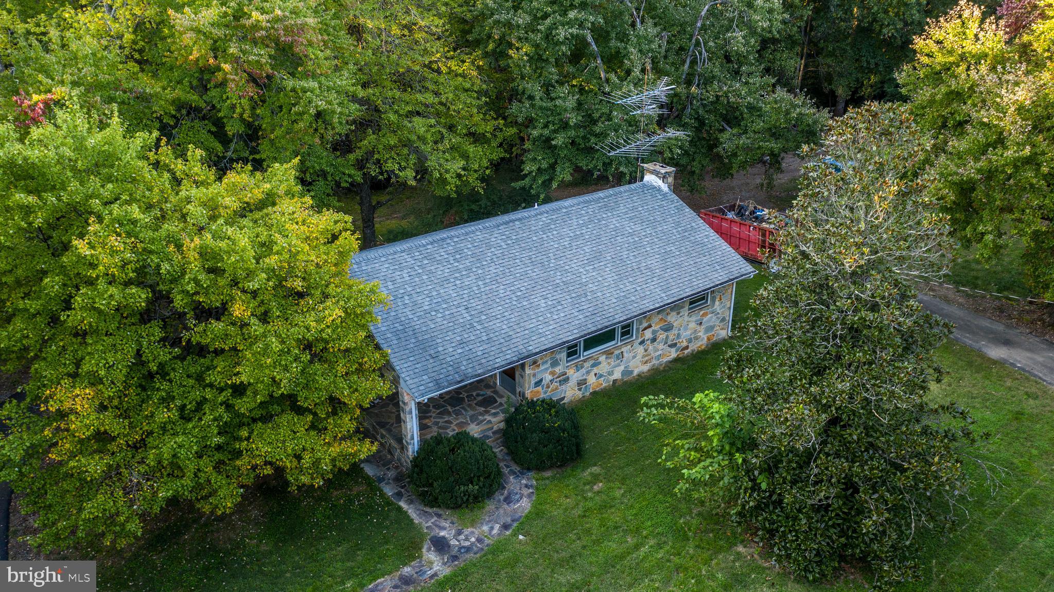 an aerial view of a house around side of green forest