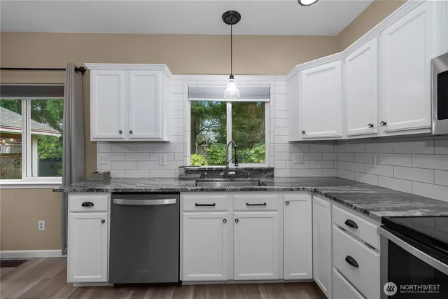 a kitchen with granite countertop white cabinets and a window