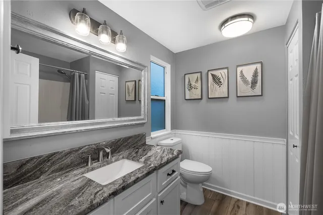 a bathroom with a granite countertop toilet a sink and mirror