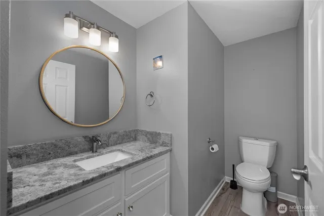 a bathroom with a granite countertop toilet a sink and mirror