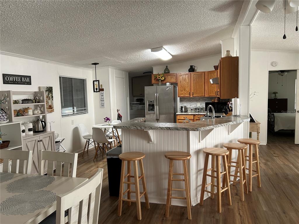 55624 Sam Street Astor, FL 32102 - Photo 9 of 12 a kitchen with stainless steel appliances kitchen island granite countertop a dining table chairs and a refrigerator