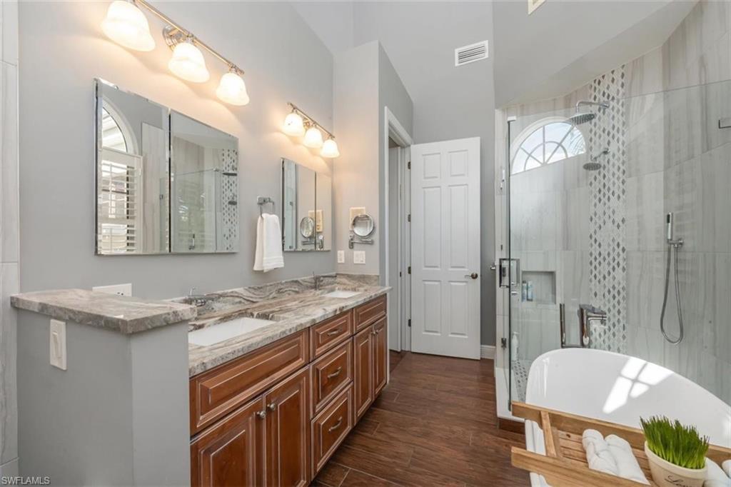 1180 Clam Court Naples, FL 34102 - Photo 13 of 38 a bathroom with a granite countertop sink a mirror a bathtub and shower