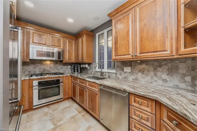 a kitchen with stainless steel appliances granite countertop a stove a sink and a microwave