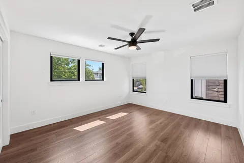 a view of a big room with wooden floor and windows