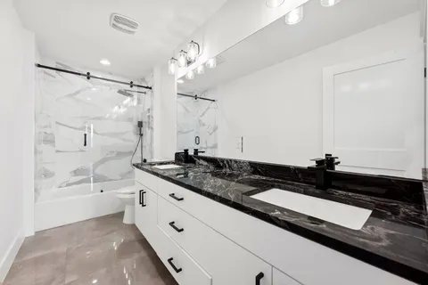 a bathroom with a double vanity sink a mirror and a bathtub
