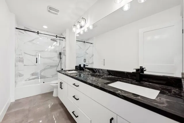 a bathroom with a double vanity sink a mirror and a bathtub
