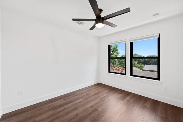 an empty room with wooden floor and windows