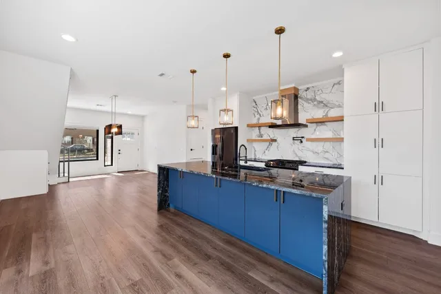 a kitchen with stainless steel appliances granite countertop a stove a refrigerator a sink and a wooden floors