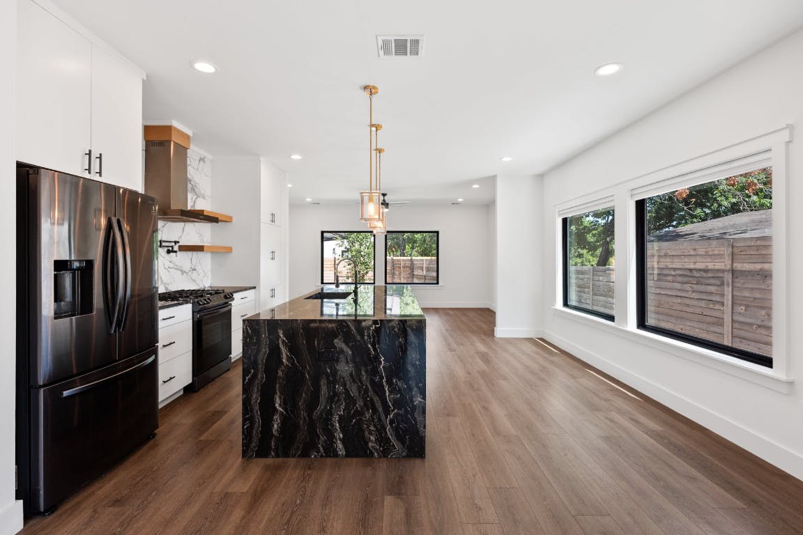 7008 Meador Avenue, Unit 1 Austin, TX 78752 - Photo 7 of 28 a kitchen with stainless steel appliances granite countertop a refrigerator a oven a sink with wooden floors