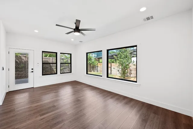 a view of an empty room with wooden floor and a window