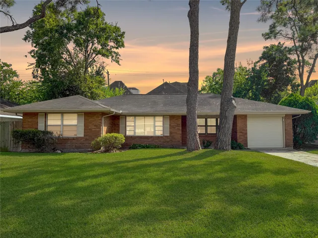 a view of a house with a big yard and large trees