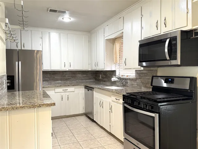 a kitchen with stainless steel appliances granite countertop a stove microwave sink and refrigerator