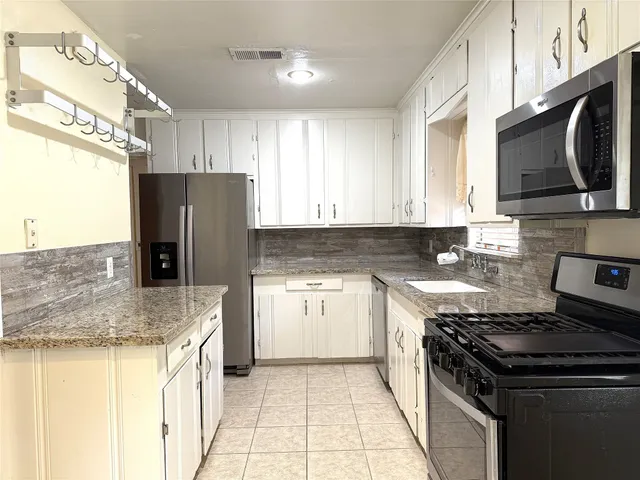 a kitchen with stainless steel appliances granite countertop a stove refrigerator sink and microwave