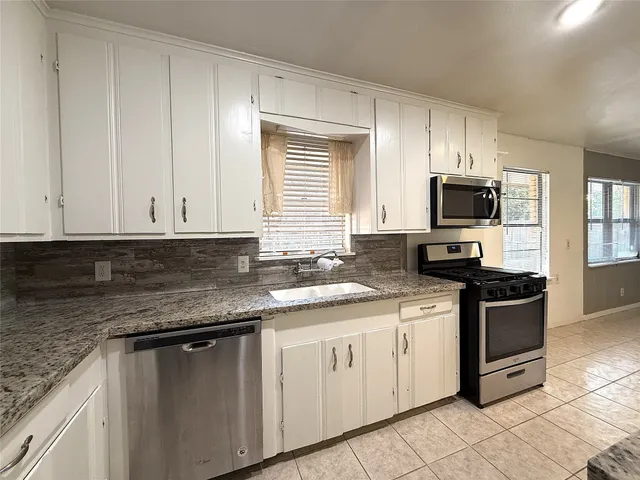 a kitchen with granite countertop white cabinets stainless steel appliances and a sink