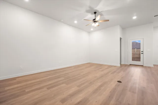 an empty room with wooden floor and fan