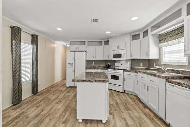a kitchen with stainless steel appliances granite countertop a refrigerator sink and white cabinets