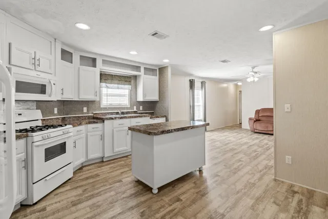 a kitchen with granite countertop a sink stainless steel appliances white cabinets and a window