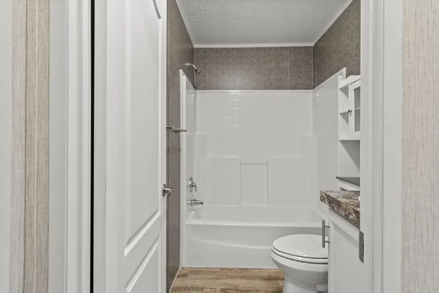 a bathroom with a granite countertop toilet sink and mirror
