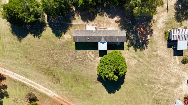 an aerial view of a house with a yard and large trees