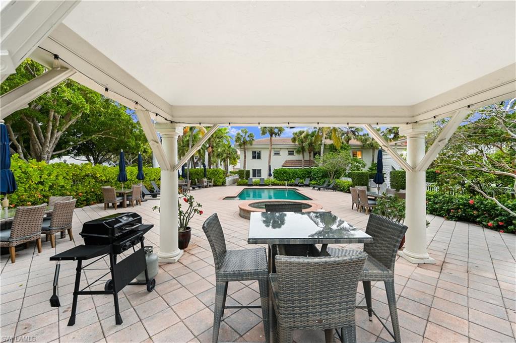 950 7th Avenue South, Unit 26 Naples, FL 34102 - Photo 14 of 15 a view of a patio with a table chairs and a floor to ceiling window