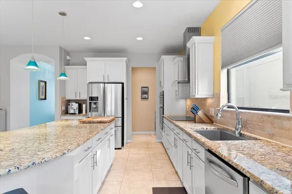 a large kitchen with granite countertop a sink and refrigerator