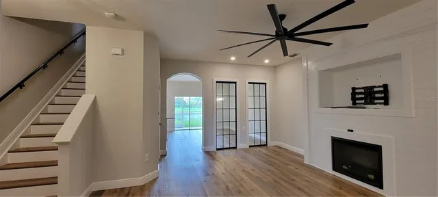 a view of an empty room with wooden floor fireplace and a window