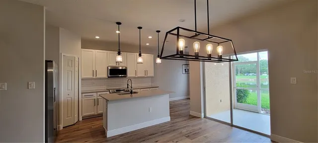 a kitchen view with a refrigerator and a wooden floor