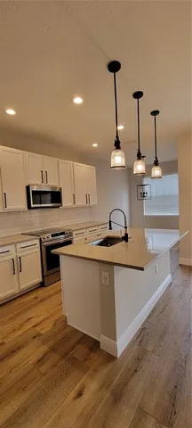 a kitchen with stainless steel appliances granite countertop a sink a stove and a wooden floors