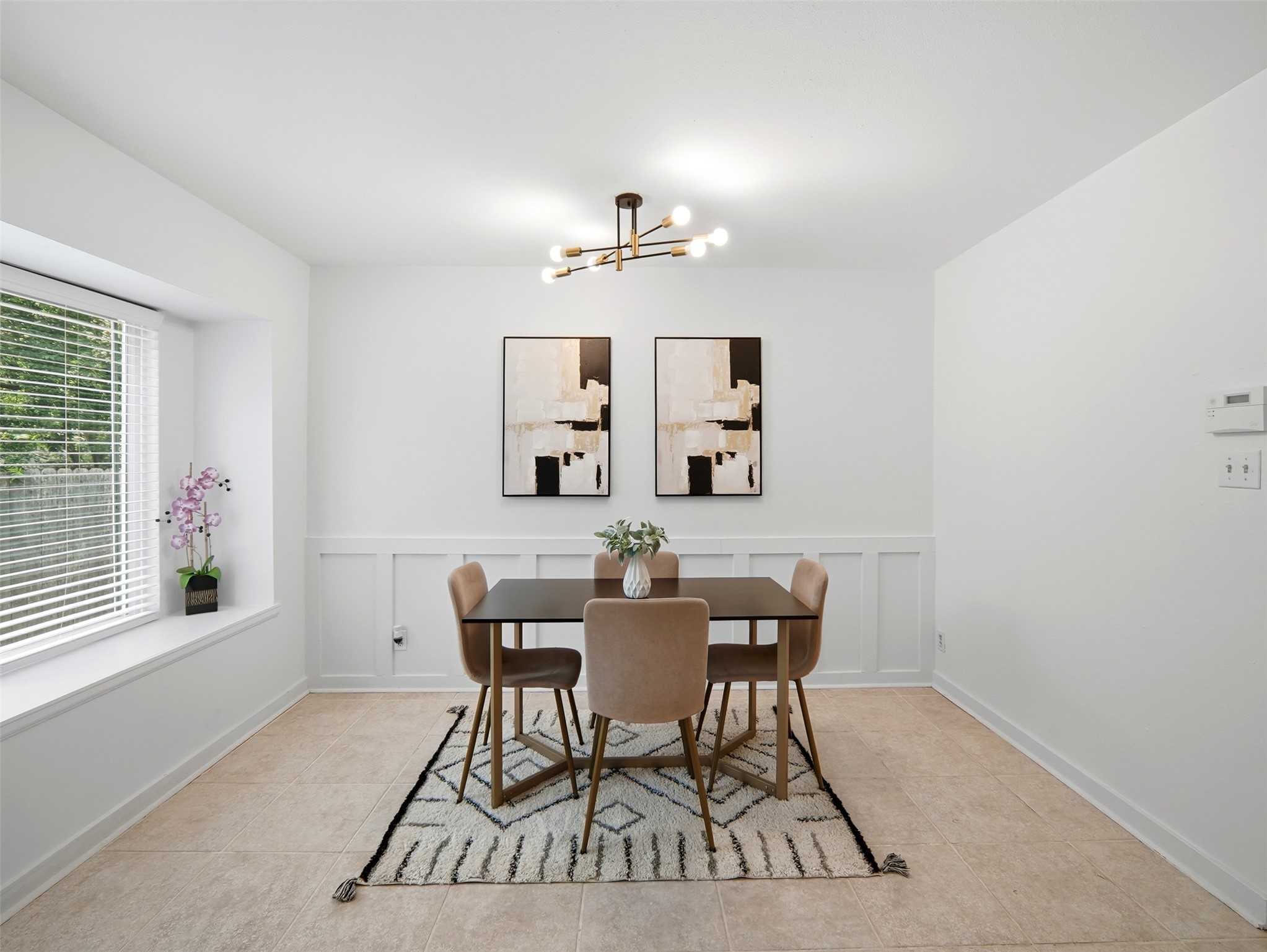 7001 Windrift Way Austin, TX 78745 - Photo 8 of 17 The elegant chandelier illuminates the dining area, featuring classic wainscoting and a generously sized window for natural light.