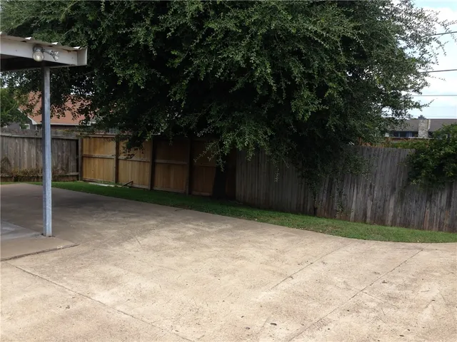 a view of a backyard with large trees and wooden fence