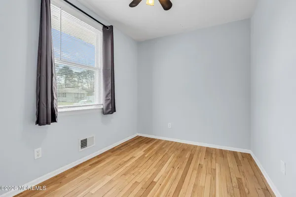 a view of room with window ceiling fan and wooden floor