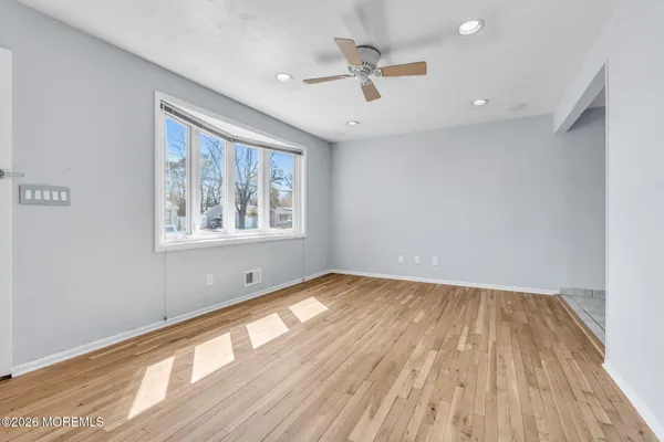 a view of an empty room with wooden floor and a window