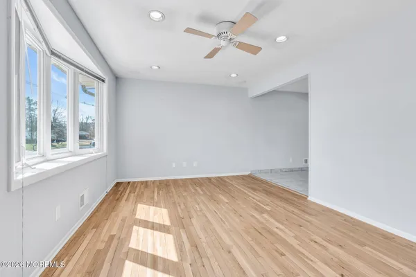 a view of empty room with wooden floor and fan