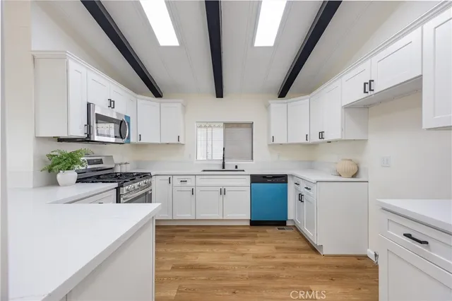 a kitchen with stainless steel appliances white cabinets a sink a stove a refrigerator and microwave