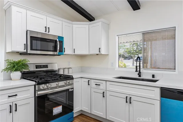 a kitchen with granite countertop white cabinets appliances a potted plant and a window
