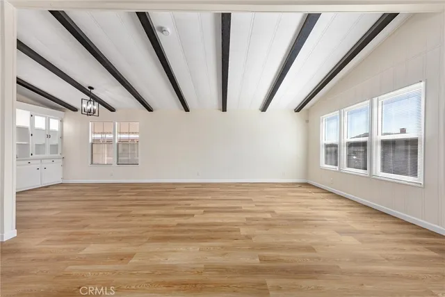 a view of an empty room with wooden floor and windows