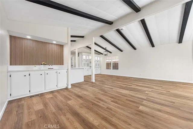 a view of an empty room with wooden floor and cabinet