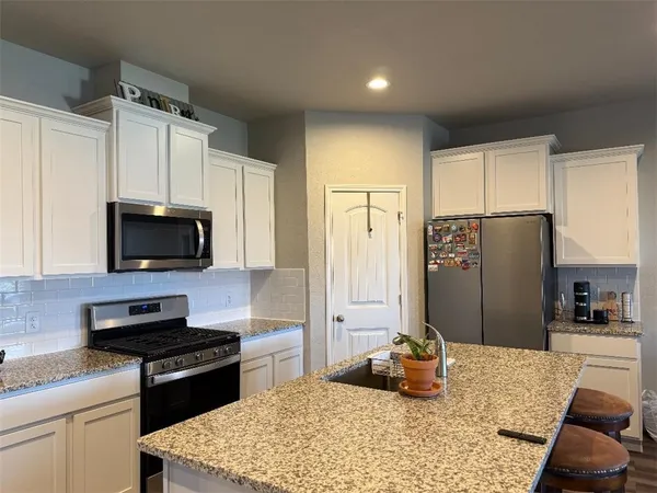a kitchen with kitchen island granite countertop a refrigerator stove top oven and sink