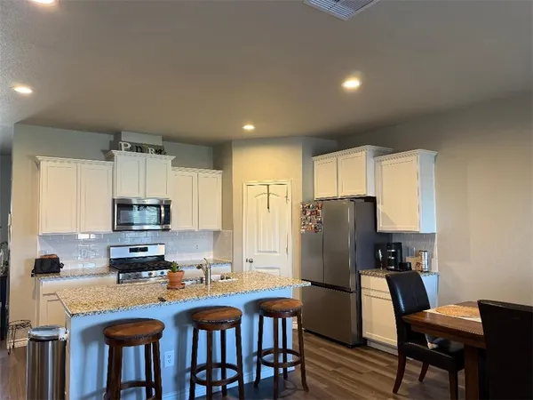 a kitchen with stainless steel appliances granite countertop a refrigerator and a stove top oven