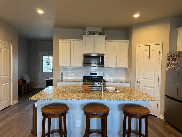 a kitchen with granite countertop a sink and a refrigerator