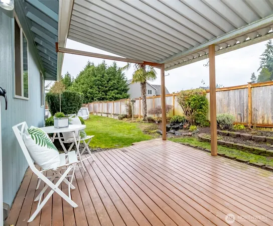a view of a patio with table and chairs wooden floor and fence with a big yard