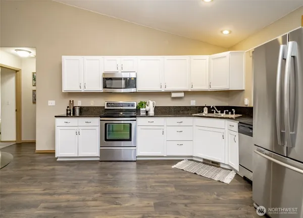 a kitchen with granite countertop white cabinets and stainless steel appliances