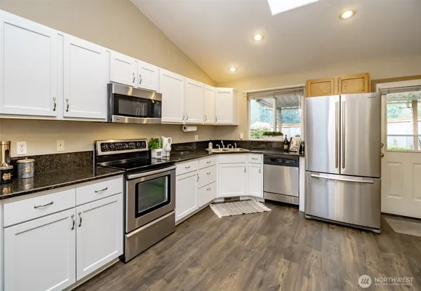 a kitchen with cabinets stainless steel appliances a sink and a window