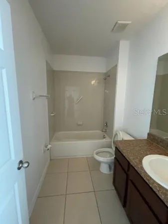 a bathroom with a granite countertop sink a toilet and shower